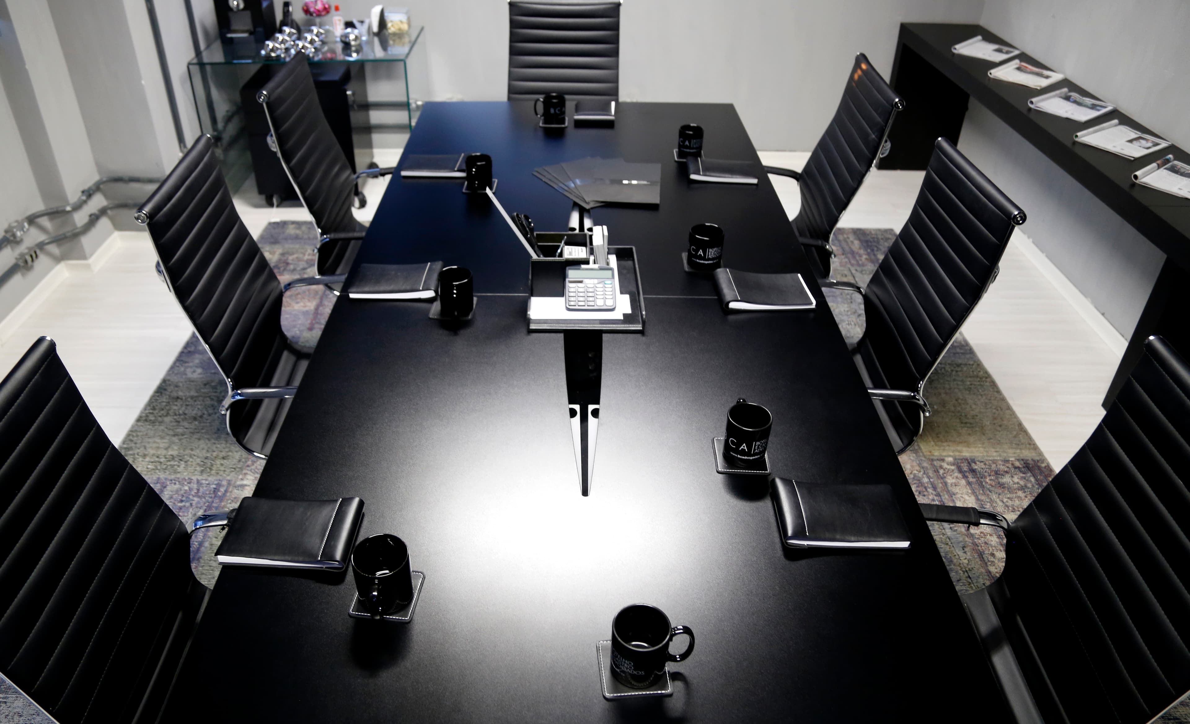 Sala de reunião executiva do JHCM Coworking com mesa preta e cadeiras ergonômicas